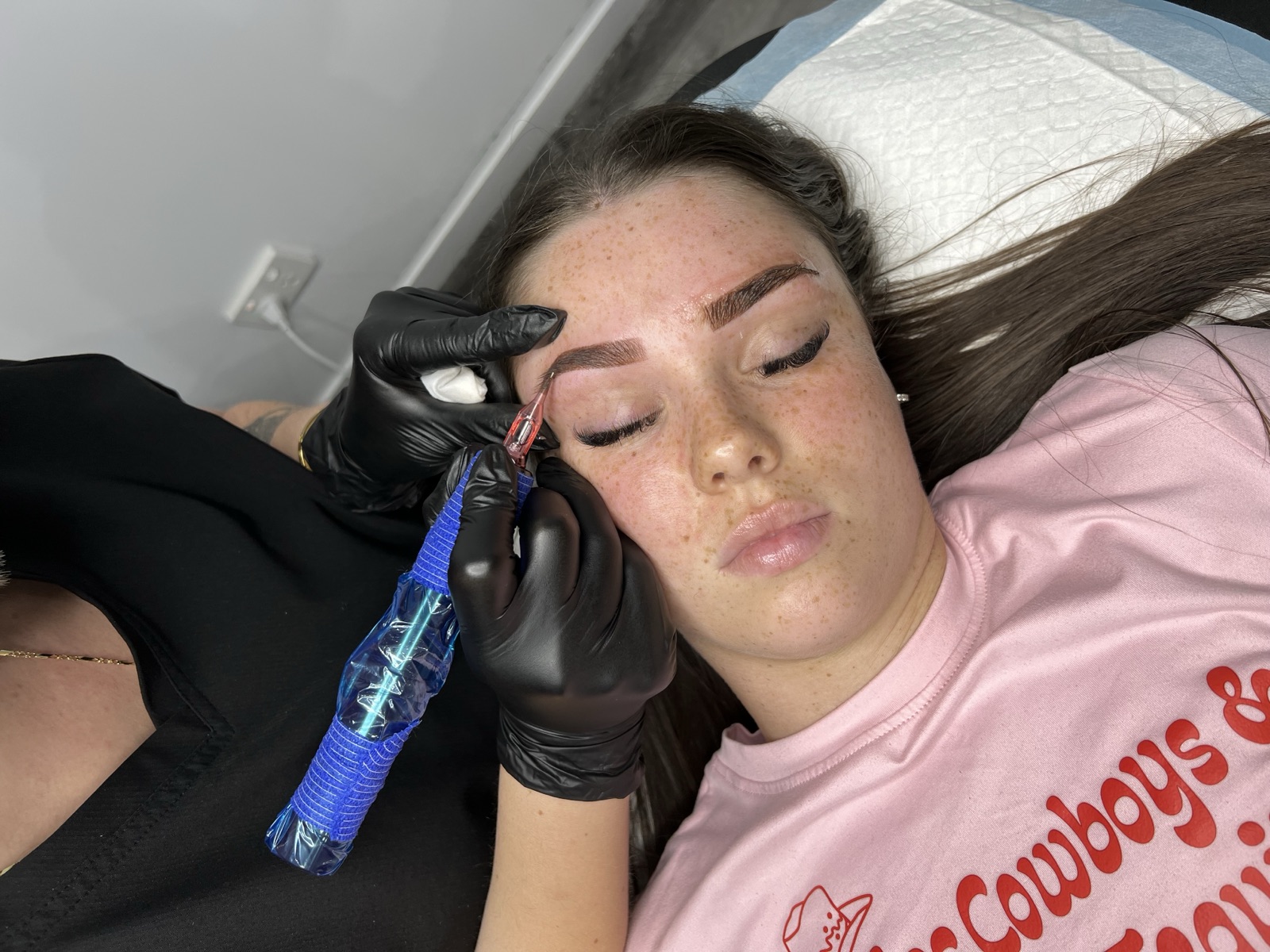 Uliana placing pigment during a cosmetic brow tattoo session